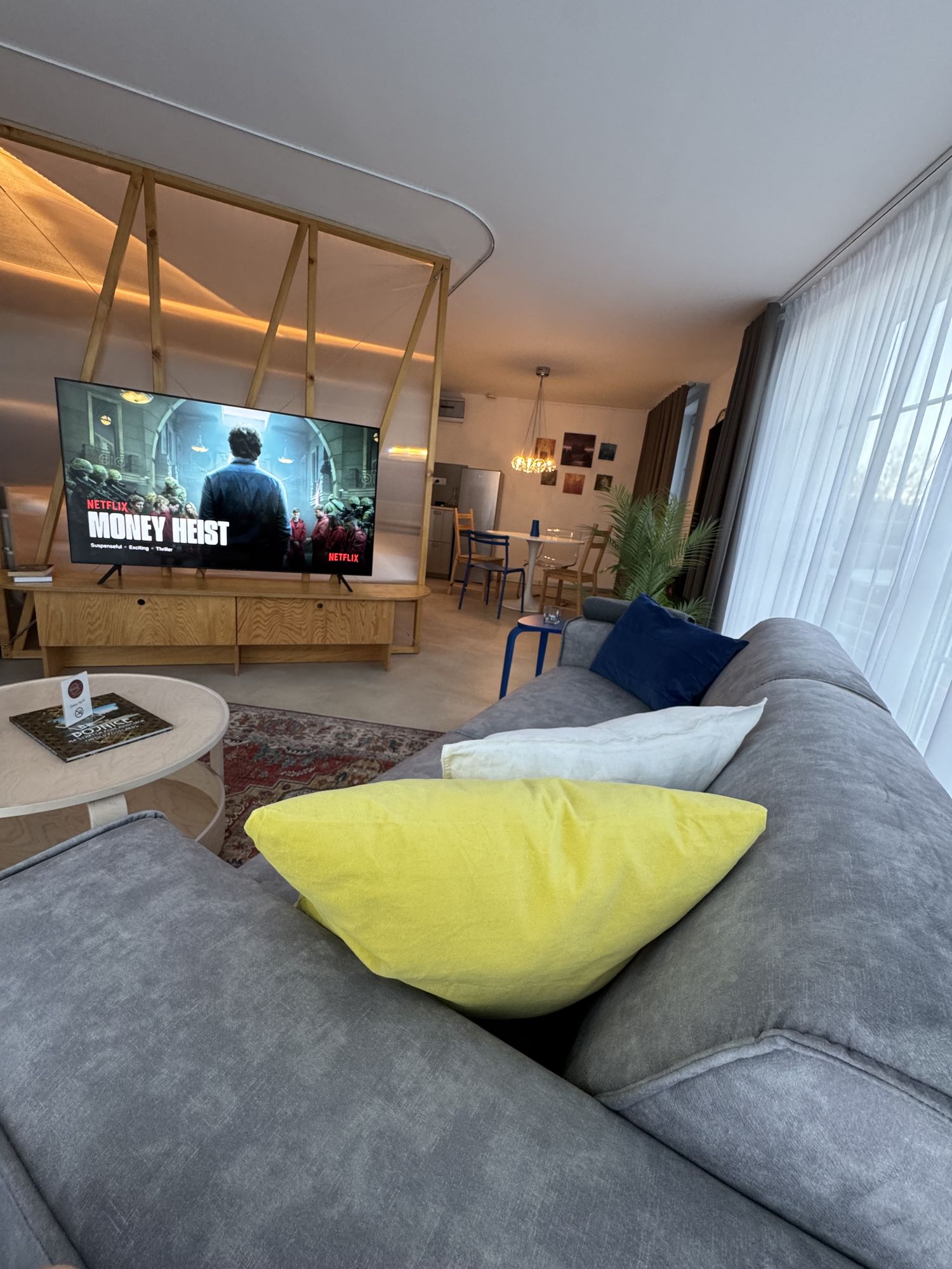 Pohodlná pohovka so žltým vankúšom a Smart TV